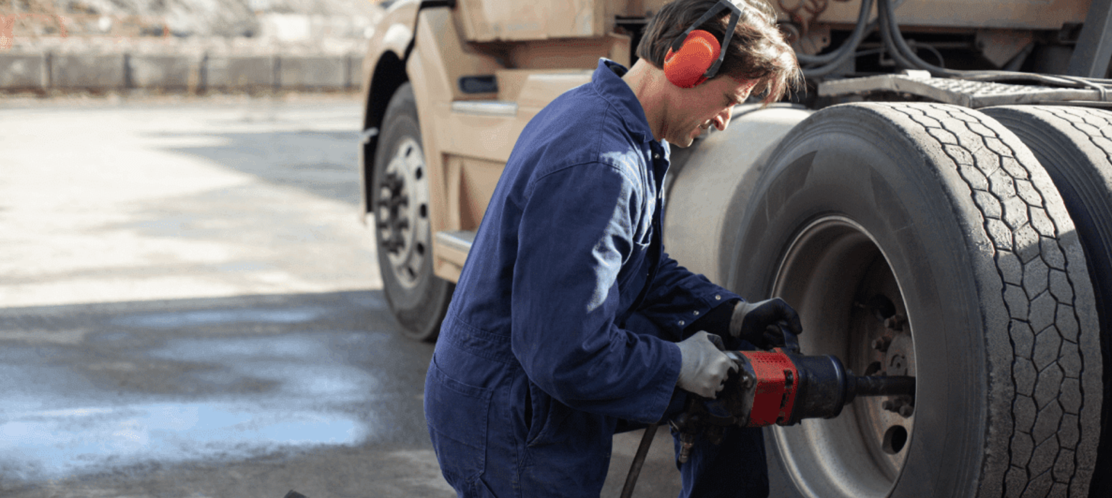Worker in protective gear operating heavy machinery outdoors.