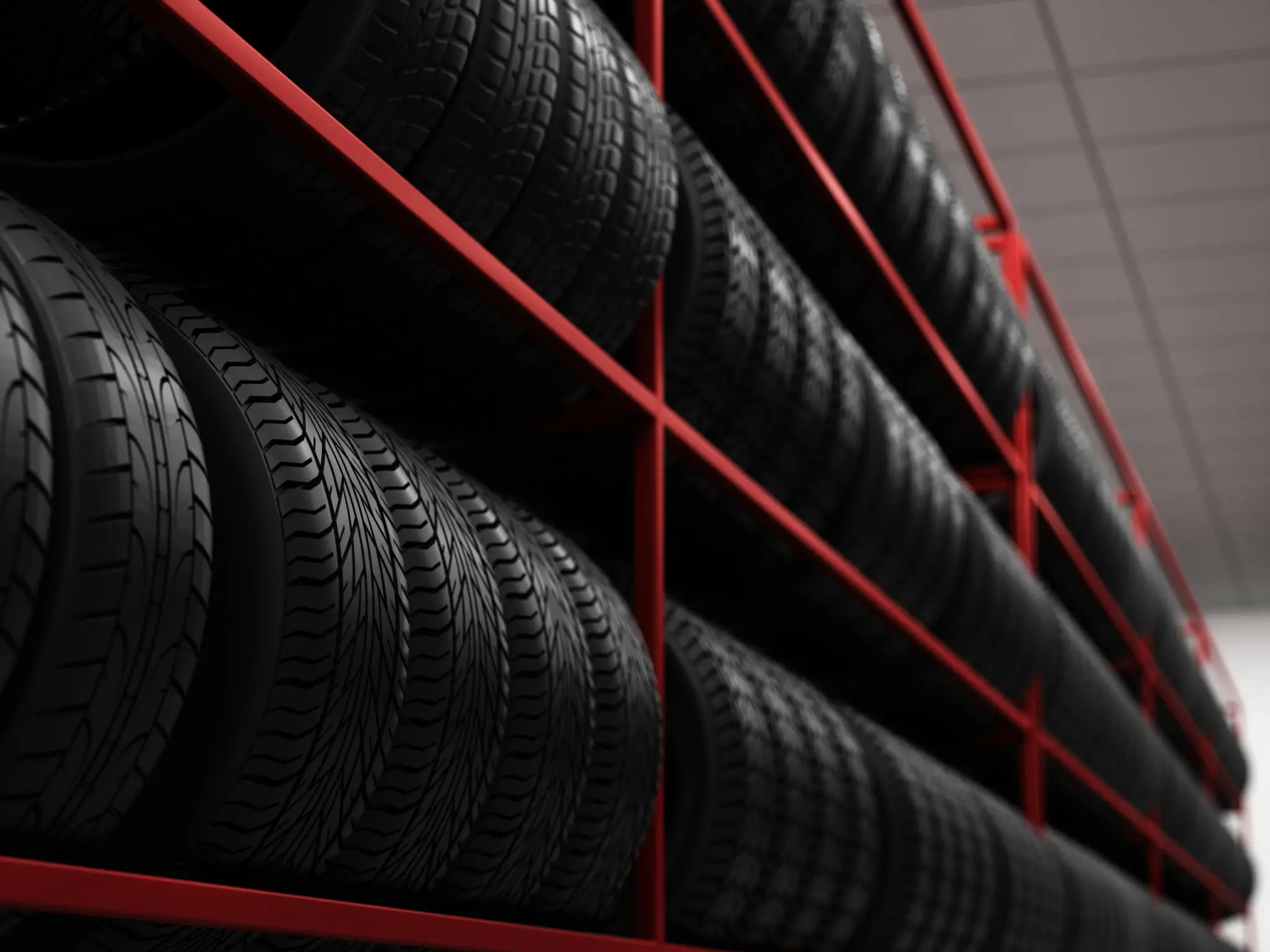Stacked car tires stored on red metal racks in a dimly lit space.